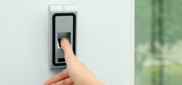Young woman scanning fingerprint on alarm system indoors